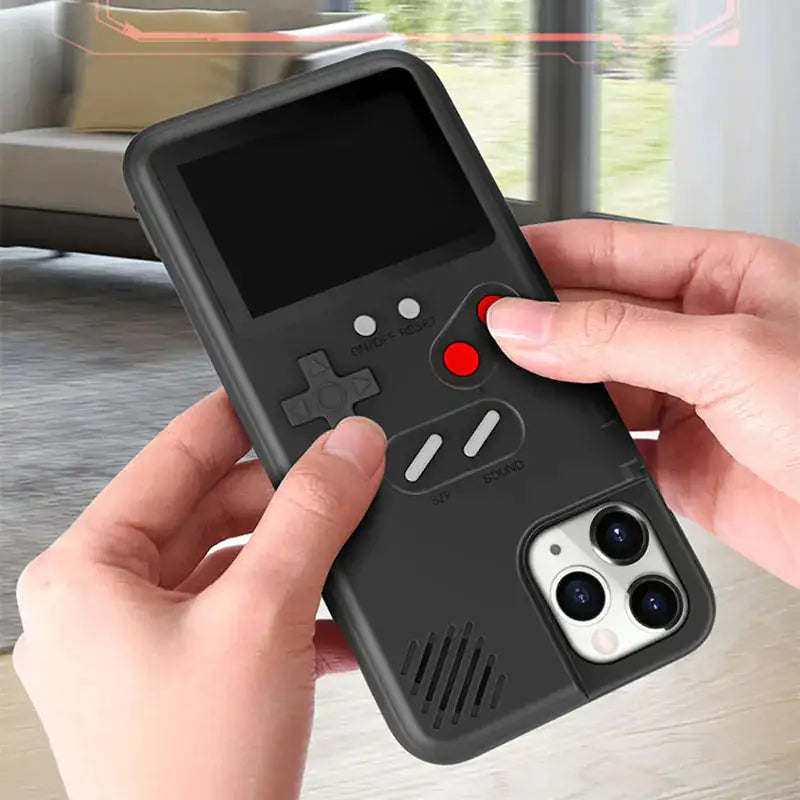 Hands holding a black Gameboy-style iPhone case with thumbs on the directional pad and red game buttons